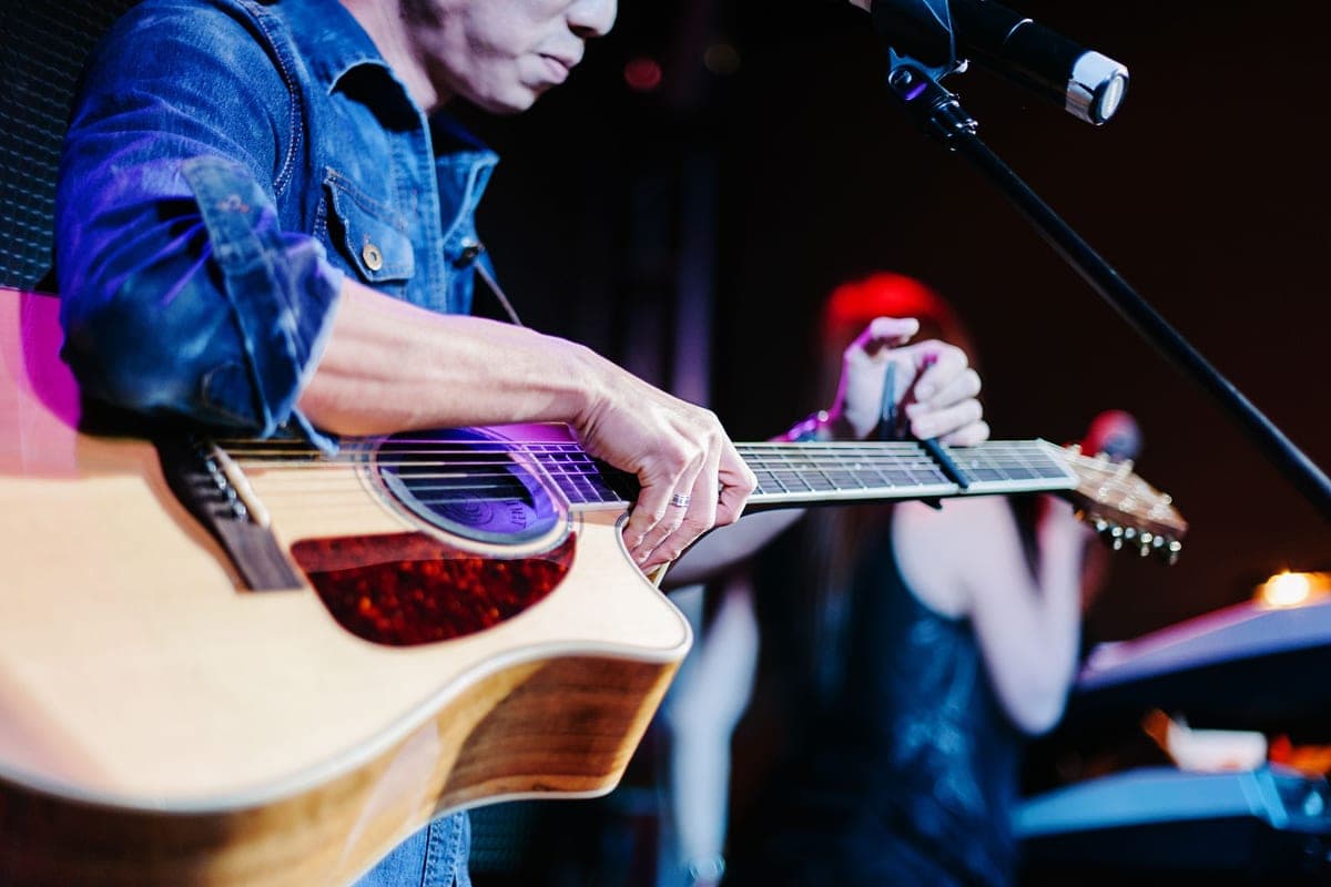 A guitarist playing an acoustic guitar live