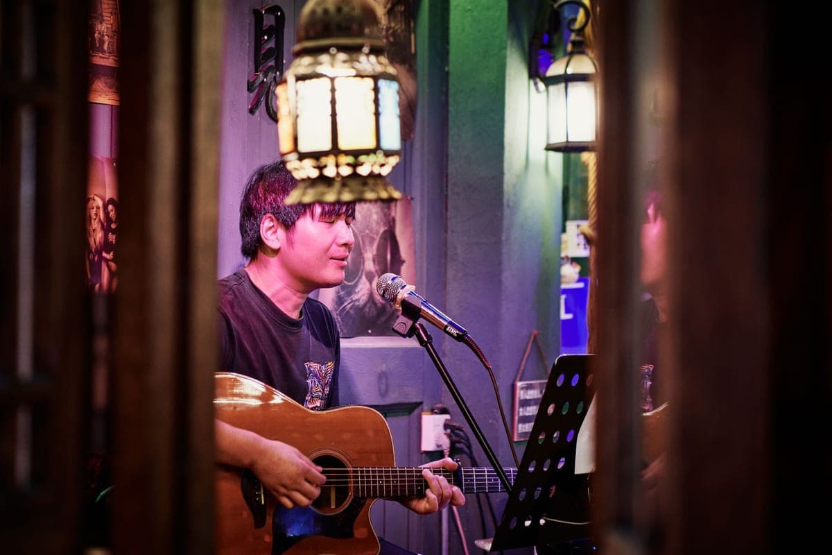 A musician playing an acoustic guitar and singing at an indoor venue