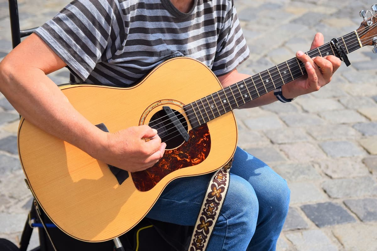 A musician playing an acoustic guitar standing up