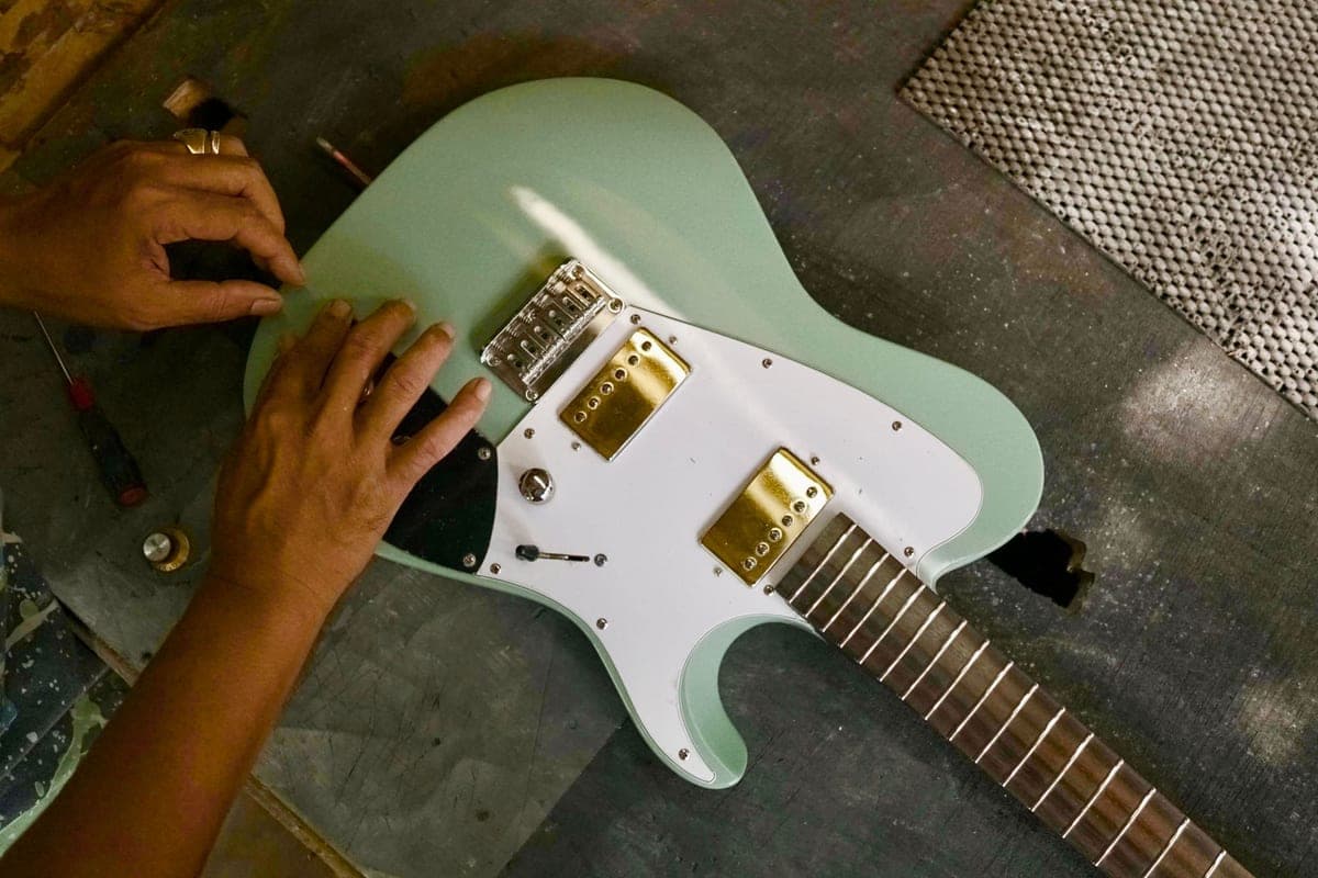 A guitar on a workbench during assembly, with tools laid out