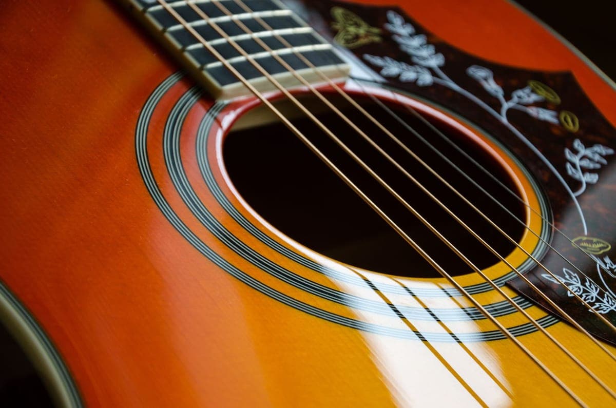 A hygrometer beside an acoustic guitar in a case
