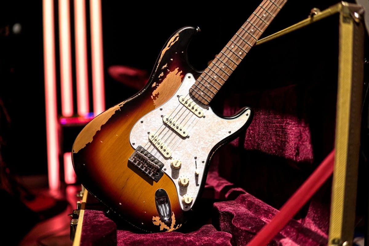 An electric guitar resting in an open lined hard case