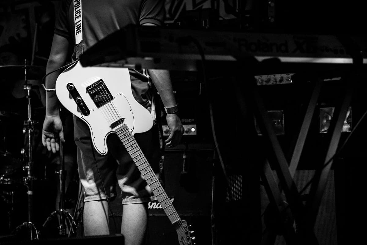 A black and white photograph of a musician with an electric guitar on a strap