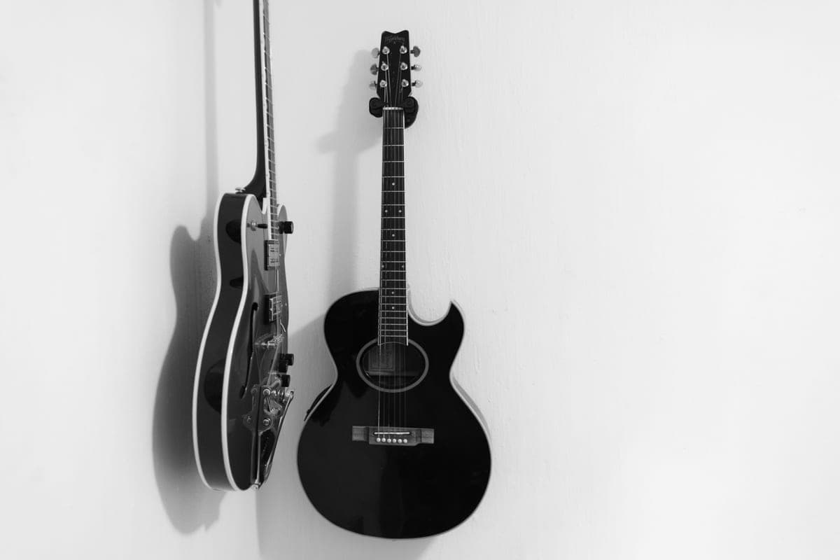 A black acoustic guitar and an electric guitar hanging side by side