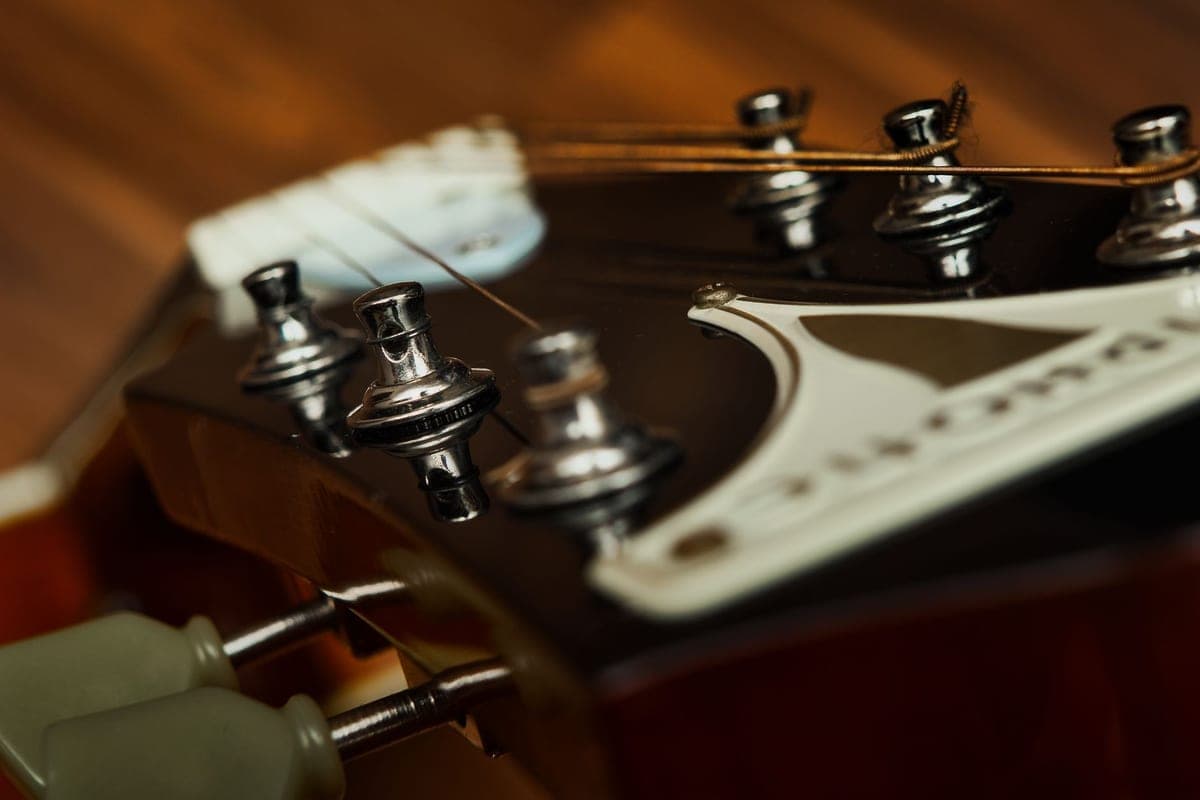 An extreme close-up of an acoustic guitar headstock, strings and tuners