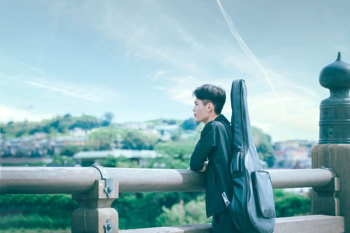 A traveler carrying a guitar case