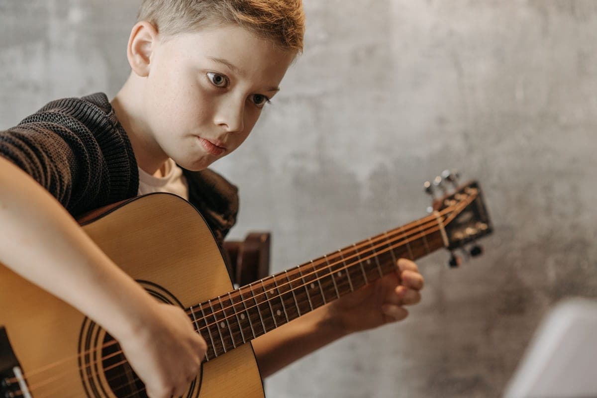 A young boy playing an acoustic guitar indoors