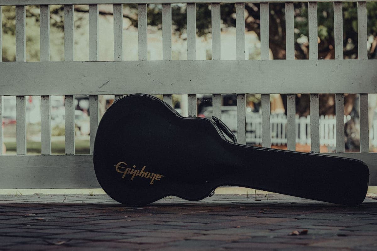A guitar gig bag beside a hardshell case