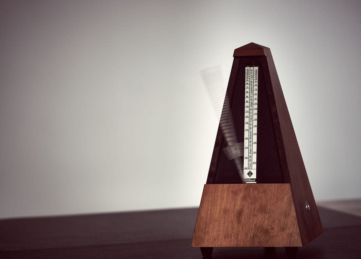 A digital metronome beside a guitar