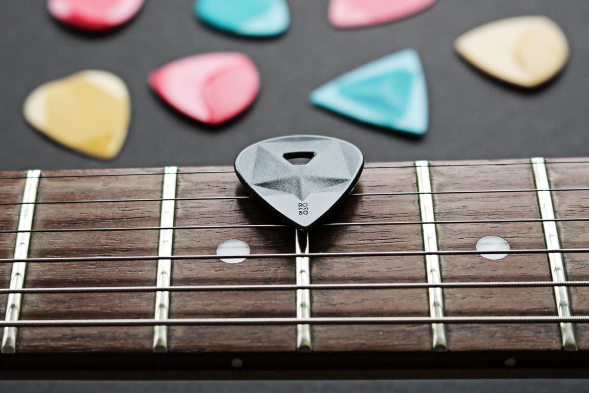 Colorful plectrums resting on a guitar fretboard