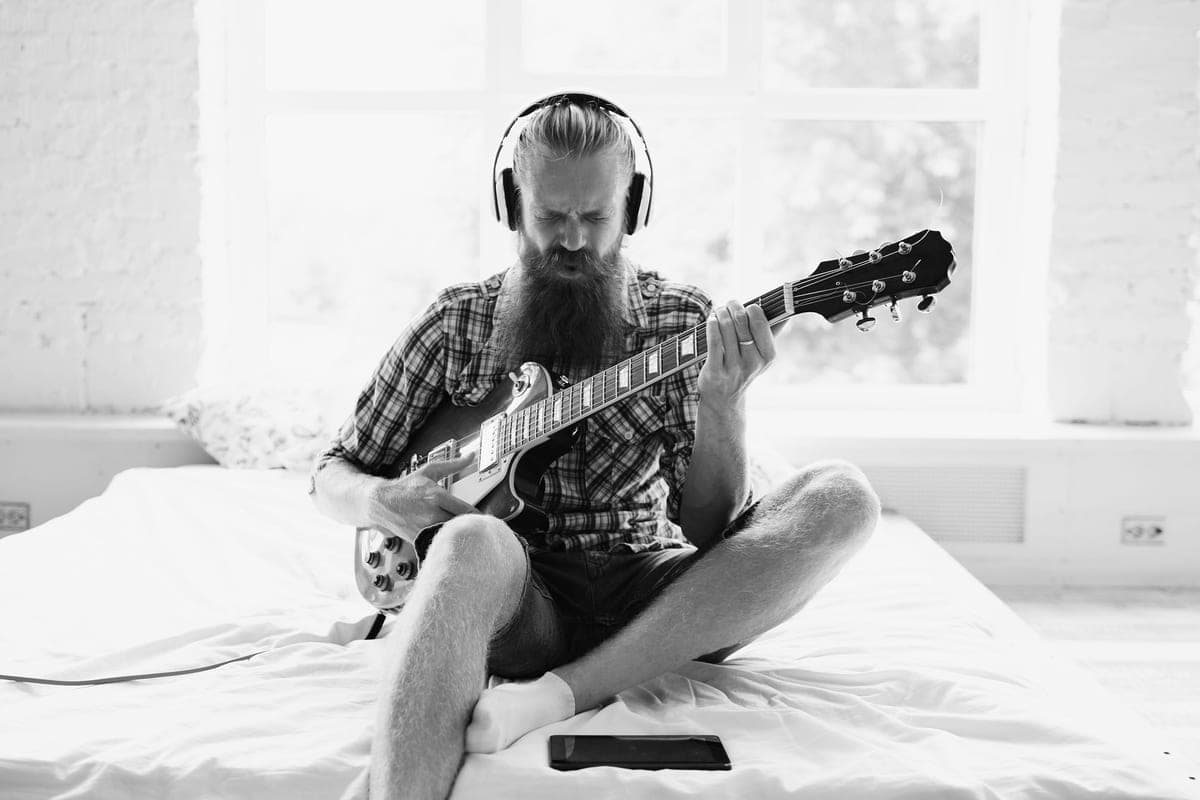 A player practicing an electric guitar wearing closed-back headphones