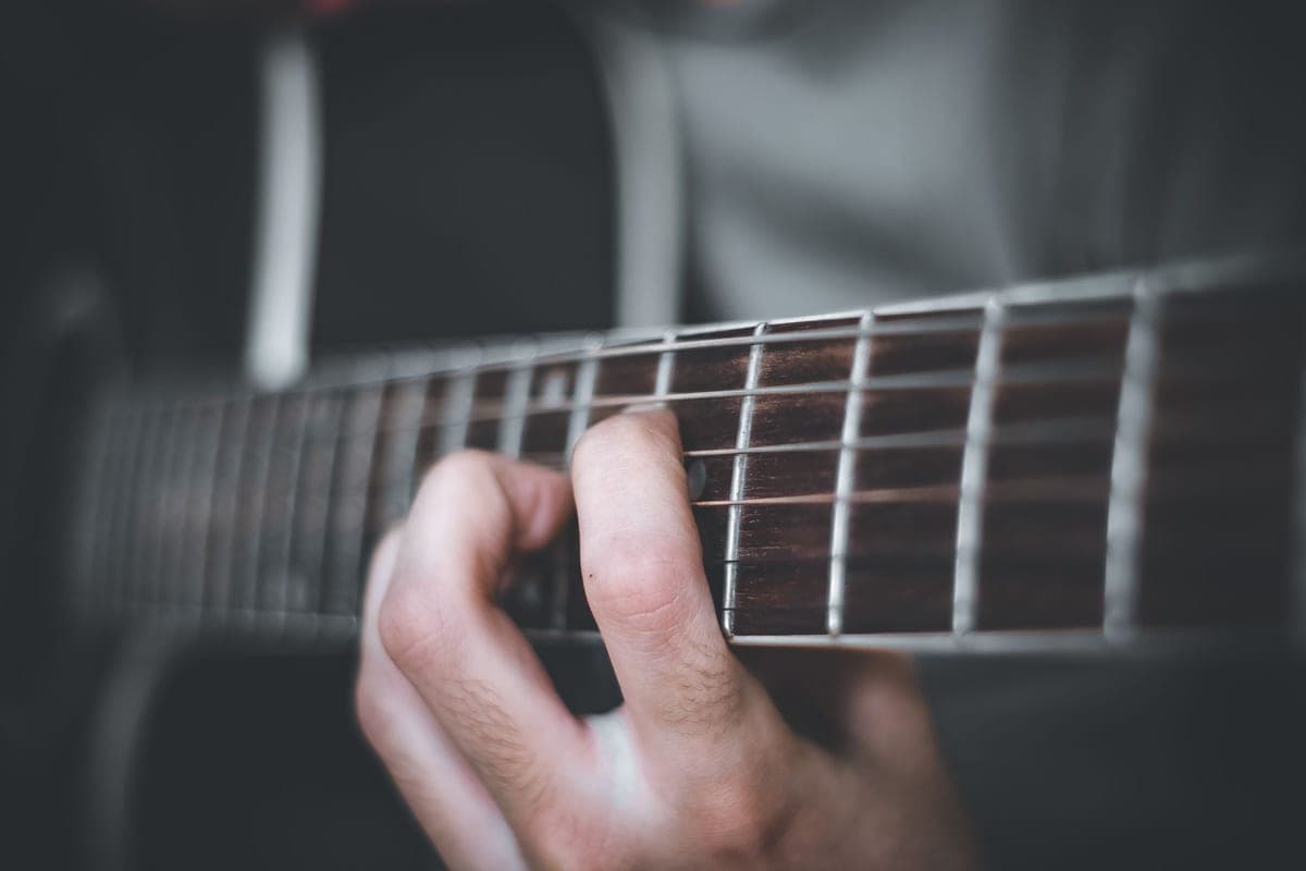 Fingers playing chords on a steel-string acoustic guitar