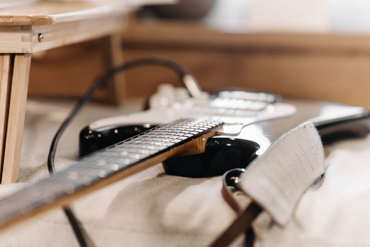 A strap end fastened to a strap button on a guitar body