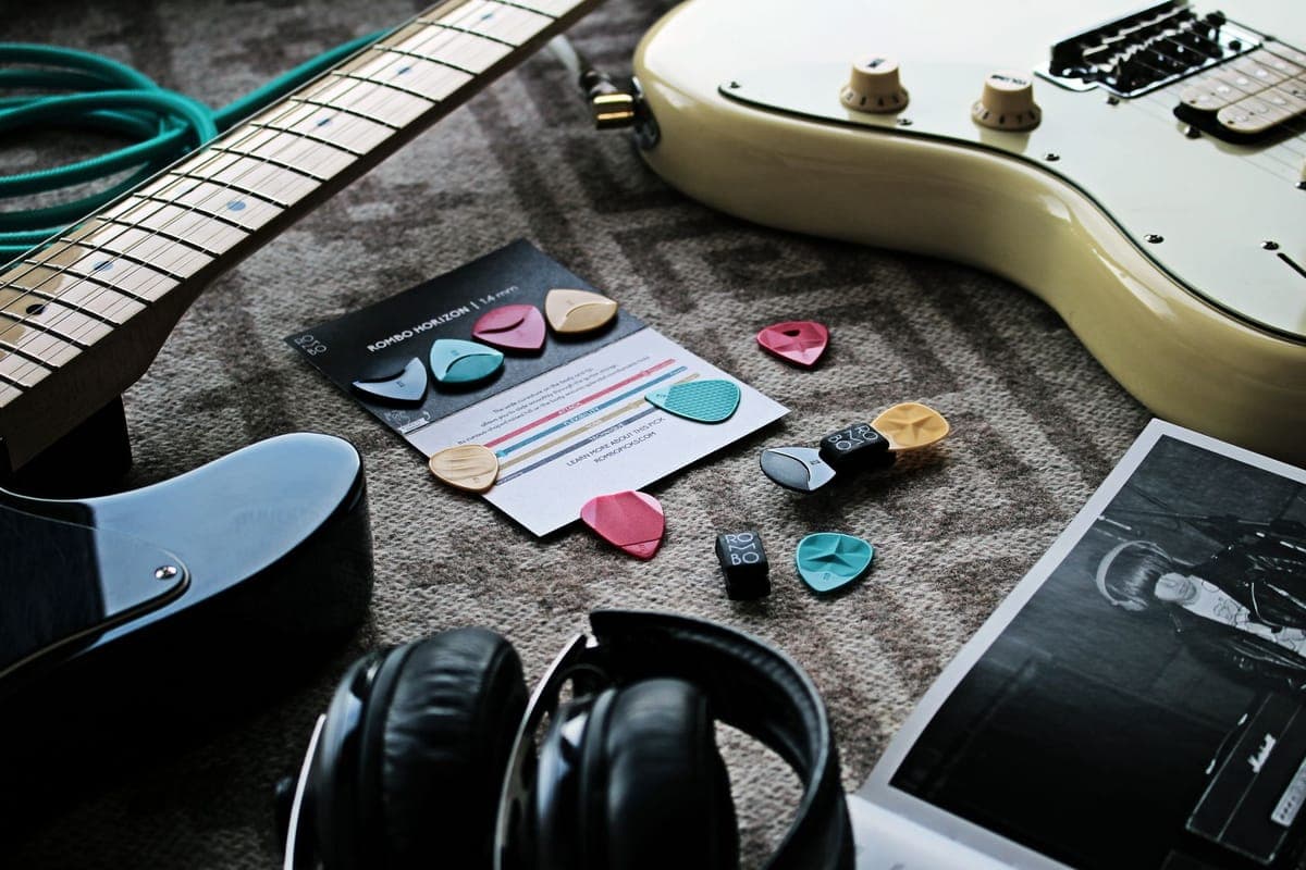Guitar accessories including picks, a capo and a strap laid out together