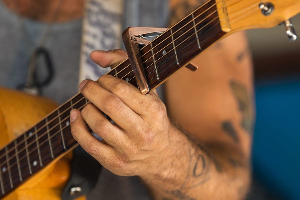 A capo clamped across the second fret of an acoustic guitar